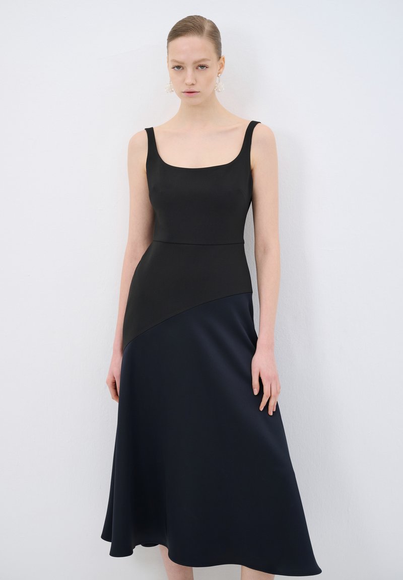 Schwarzes und navy Kleid mit quadratischem Ausschnitt, ärmellosem Design und asymmetrischem Saum. Glattes Material mit einem dezenten Glanz.