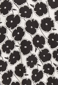 Des fleurs de pavot abstraites noires avec des centres blancs et des tiges fines sur un fond blanc, formant un motif floral répétitif.
