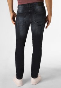 Jeans slim-fit, de culoare albastru închis, cu un ușor luciu, având două buzunare pe spate și o ușoară decolorare. Asortați cu adidași de culoare deschisă.