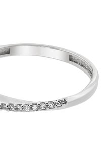 Bague argentée élégante présentant un design incurvé avec de petits cristaux clairs incrustés sur un côté, mettant en valeur une surface polie et réfléchissante.