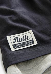 Tissu sombre avec une finition texturée, featuring une étiquette blanche qui indique "Authentique Produits de Qualité Établis en 1982." Accentué par un bord gris clair.