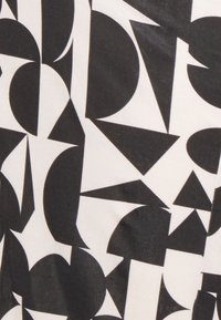 Tecido preto e branco com um padrão geométrico de várias formas, incluindo círculos, triângulos e curvas, sobre uma superfície lisa.