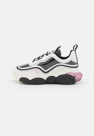 Zwart-witte chunky sneaker met golvend ontwerp, gestructureerde zool, glanzende en glinsterende accenten en een roze doorzichtige hieldetail.