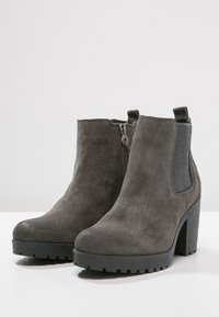 Stivaletti alla caviglia in suede grigio con tacco spesso e pannelli laterali testurizzati. Dotati di chiusura con zip e suola robusta per una migliore aderenza.