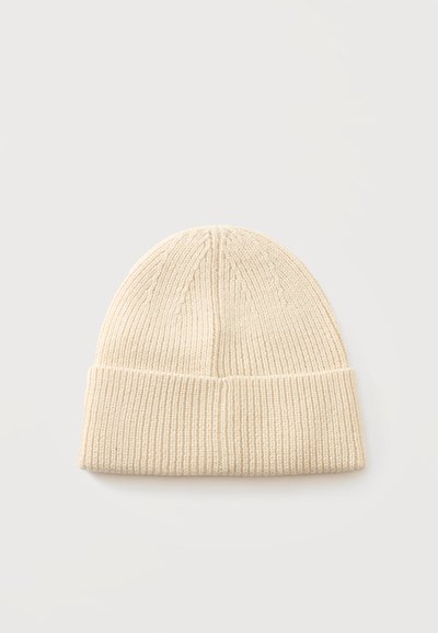 Bonnet beige en maille avec revers plié, présenté à plat sur fond blanc.