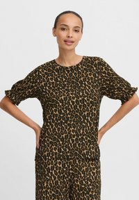 Top s leopardím potiskem vyrobený z lehkého materiálu, s kulatým výstřihem, krátkými rukávy se zúženými manžetami a volným střihem.