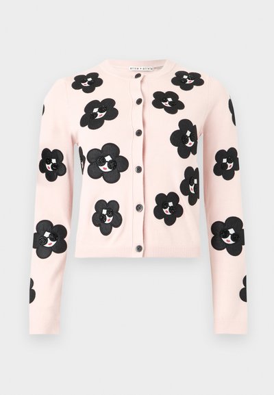 Ανοιχτό ροζ πουλόβερ με κουμπιά και μαύρα μπαλώματα λουλουδιών με χαμογελαστά πρόσωπα που φοράνε γυαλιά ηλίου.