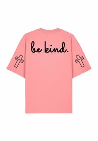 T-shirt rose oversize avec le texte "be kind." dans le dos et des croix noires sur les deux manches avec l'étiquette "Karma Kills."