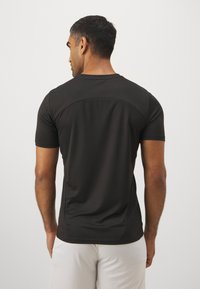 Maglietta atletica nera a maniche corte con una texture liscia, caratterizzata da un colletto arrotondato e una discreta lavorazione delle cuciture sul retro.