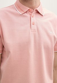 Polohemd aus softem rosa Baumwollstoff mit strukturiertem Gewebe, einer Knopfleiste mit zwei Knöpfen und einem kontrastierenden weißen Kragen mit Streifen, besticktem Logo-Detail.