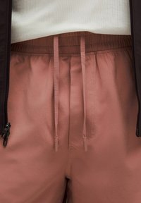 Fényes rózsaszín rövidnadrág sima anyagból, el elastic waistband, húzózsinórral és cipzáros oldalzsebbel.