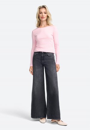 Hellrosa, langärmliges gestreiftes Oberteil, kombiniert mit hochgeschnittenen, weit geschnittenen Jeans aus dunklem Denim. Das Outfit wird mit cremefarbenen flachen Schuhen abgerundet.