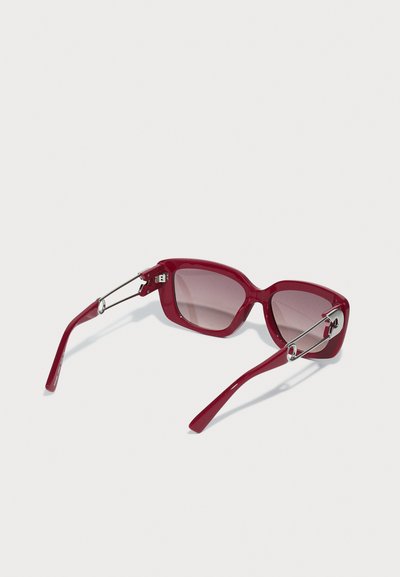 Óculos de sol vermelhos de plástico com armação quadrada e lentes degradê. Acentos metálicos nas dobradiças, hastes finas e acabamento brilhante.