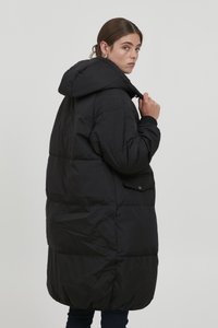 Black puffer coat with a hood, featuring a boxy design, quilted texture, side pocket, and ribbed cuffs, shown from the back.