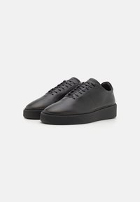 Black leather sneakers with a smooth texture, rounded toe, and flat rubber sole. Features sturdy laces and a minimalistic design.