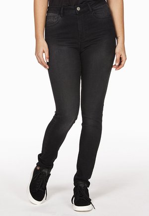 Schwarze schmale Jeans aus Denim, mit mittelhohem Bund, fünf Taschen und einer glatten Textur. Kombiniert mit schwarzen Sneakers.