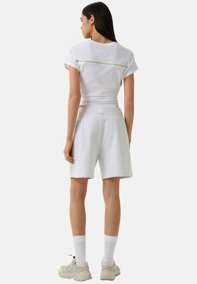 White short-sleeve t-shirt with green accent, paired with light grey shorts featuring a label at the waistband and ribbed white socks.