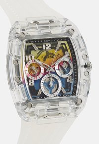 Montre en acrylique transparent avec un cadran carré, un affichage multicolore, des repères horaires métalliques et un bracelet en silicone blanc. Détails de chronographe visibles.