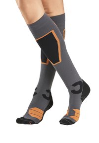 Graue kniehohe Socken mit orangen Akzenten, ausgestattet mit einer gerippten Textur und verstärktem Zehenbereich. Schwarze Schriftzüge entlang der Seiten erhöhen die Sichtbarkeit.