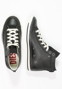 Czarne skórzane trampki wysokie z białymi sznurowadłami i gumowymi podeszwami. Posiadają okrągłe akcenty metalowe oraz kontrastową paskowaną podeszwę.