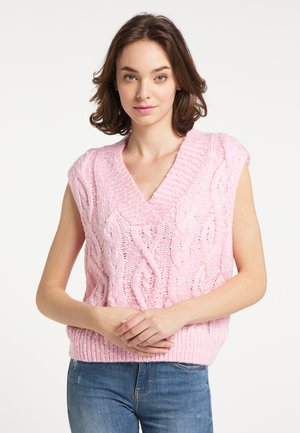 Maglione smanicato rosa chiaro a maglia con scollo a V, caratterizzato da un motivo a trecce e orlo a coste, indossato su jeans in denim.