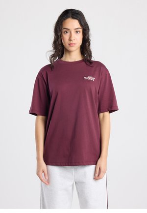 Burgundy crew-neck T-shirt made of soft cotton, featuring a small graphic detail on the chest and short sleeves. Relaxed fit design.
