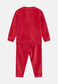 Rød velour treningsdress med langermet topp og bukser med elastisk midje, med en myk tekstur og ribbede mansjetter for komfort.