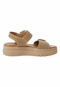 Sandale beige avec semelle épaisse plateforme, deux larges brides tissées avec boucles ajustables sur le pied et la cheville, design à bout ouvert.