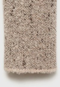 Beiger Strickstoff mit einer strukturierten Oberfläche und braunen Einsprengseln, weich im Griff und mit einem leicht ausgefransten Rand.