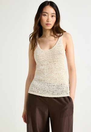 Lichtbeige gebreide tanktop met een ronde hals, een gestructureerd patroon en een aansluitende snit, gecombineerd met brede bruine broeken.