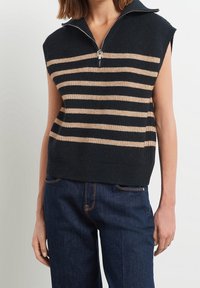 Marinblå ärmlös tröja med ljusbeige horisontella ränder, med hög krage och halv dragkedja. Stickad struktur med en lös passform.