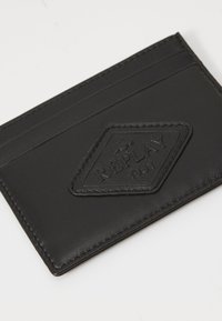 Black leather cardholder with a textured surface, featuring four card slots and an embossed diamond logo labeled "REPLAY 1981."