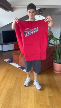 Sweatshirt vermelho com bolso frontal, apresentando um logótipo azul e branco "Gant" no peito; material em algodão, capuz com cordão e corte descontraído.