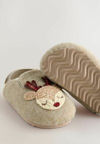 Beige Kinderhausschuhe mit einer weichen, fuzzigen Textur und einem gehäkelten Rentier-Gesicht, das eine Schuheinlage mit einem gewellten Grip-Muster zeigt.