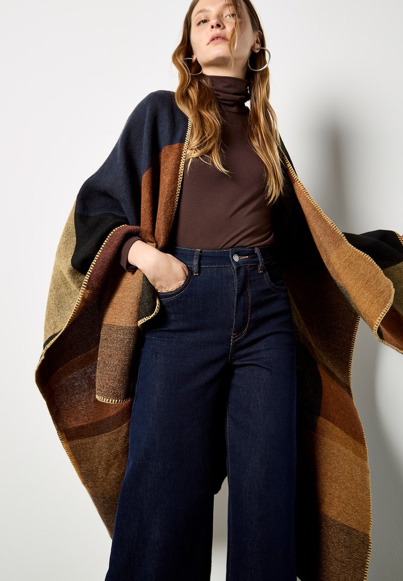 Multikleuren oversized poncho met bruine, zwarte en marineblauwe strepen, met een franjerand en van een warme, gestructureerde wolachtige stof.