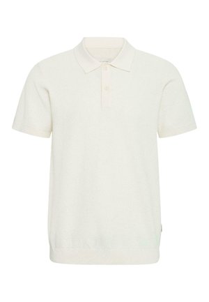 Camiseta tipo polo de manga corta en color crema con una tapeta de dos botones y un patrón de tejido texturizado, presentada sobre un fondo blanco.