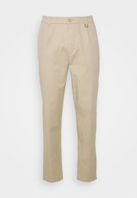 Světle béžové kalhoty se střihem rovného střihu, vyrobené z bavlněného materiálu. Mají knoflíkové zapínání, poutka na opasek a malý doplňkový kroužek.