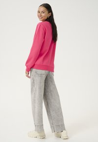 Rosa Sweatshirt mit langen Ärmeln, gerippten Bündchen und Saum, kombiniert mit hellgrauen weit geschnittenen Jeans und weißen Sneakers. Einfaches, lässiges Outfit.