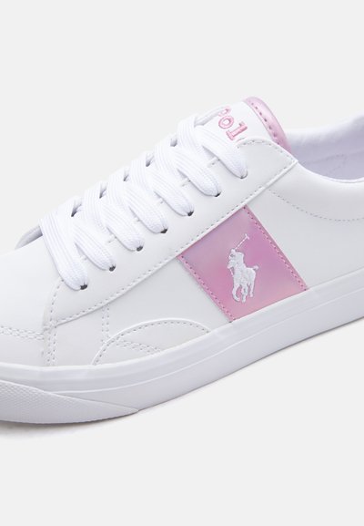 Biały tenisówka z różowymi akcentami, białymi sznurowadłami i różową łatą z białym logo gracza polo po boku.