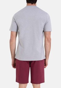 T-shirt gris à manches courtes avec un col rond, associé à un short bordeaux. Le t-shirt possède une texture en coton lisse et doux.