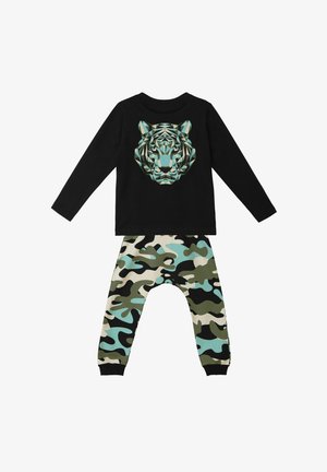 Sort langærmet skjorte med et geometrisk tiger-tryk; sat sammen med bukser med camouflage-mønster i grøn, sort og blå.
