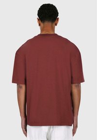 Bordeaux bomulds t-shirt med en afslappet pasform, korte ærmer og uden synlige grafikker eller udsmykninger, vist fra ryggen.