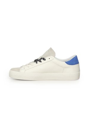Zapatilla blanca de caña baja con cordones en blanco y negro, puntera de ante beige y detalle en el talón de ante azul, vista desde el lado exterior.
