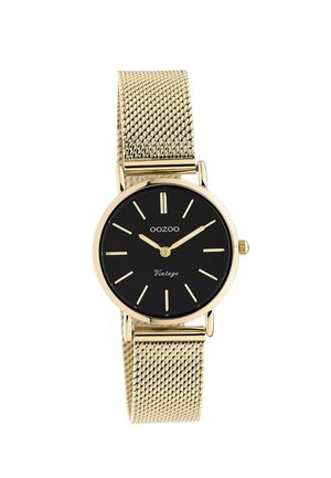 Gold mesh strap watch with a black round dial, gold hour markers, and hands. Features a "Vintage" inscription at the bottom of the dial.