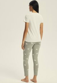White t-shirt paired with gray pajama pants featuring a leaf pattern. The outfit has a relaxed fit and is made from soft fabric.