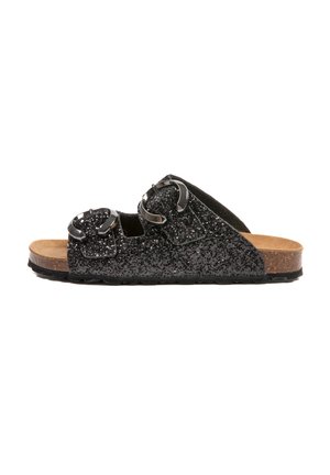 Sandale à glissière noire en paillettes avec des bretelles réglables doubles, des boucles métalliques et un semelle en liège, présentant une semelle extérieure en caoutchouc texturé.