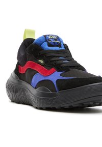 Černé tenisky s texturovaným svrškem, zdobené modrými, červenými a fialovými prvky, tlustou černou podešví a jasně žlutým podpůrným páskem na patě.