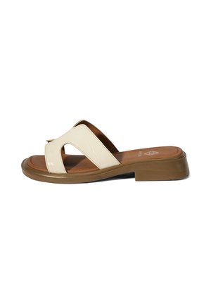 Beige offene Sandale mit breiten gekreuzten Riemen und niedriger brauner Sohle, für den Freizeitgebrauch konzipiert.