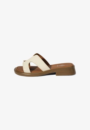 Sandale beige à bout ouvert avec larges brides croisées et semelle basse marron, conçue pour un usage décontracté.