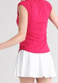 Tight rosa idrottstopp med korta ärmar, kombinerad med en utsvängd vit kjol. Slät textur, lätt material och enkel design.